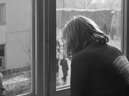 En flicka tittar ut från ett fönster som krossats av bomberna