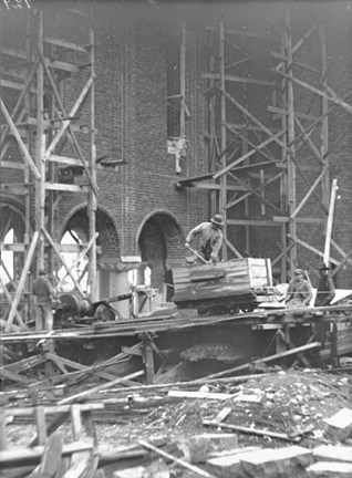 Byggnadsställningar i trä och maskiner vid Stadshusets fasad. Några arbetare.