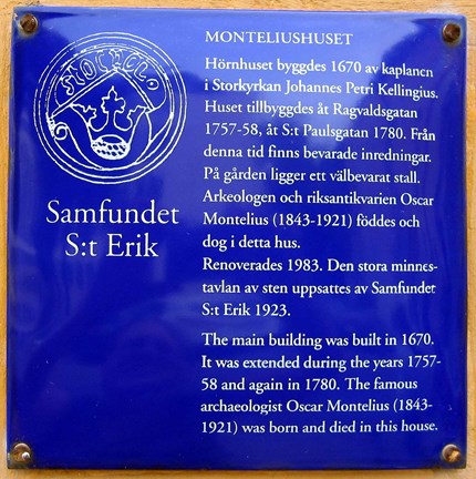 Blå emaljskylt med vit text om Monteliushuset