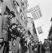 Fredsdagen den 7:e maj 1945. 
Flaggviftande människor firar freden längs Mäster Samuelsgatan.