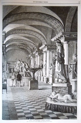 Två personer tittar på skulpturer i en långmal sal med välvt tak och rutigt golv