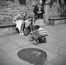 Ungt par som fotograferar sitt barn, sittandes i barnvagn