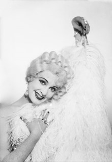 Porträtt, förmodligen rollporträtt, av sångerskan och skådespelerskan Zarah Leander med vit peruk och svandunsboa