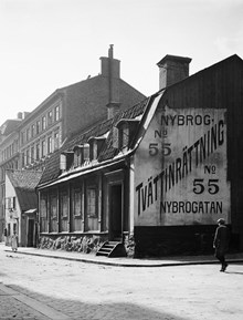 Nybrogatan söderut från Östermalmsgatan. Nybrogatan 55 (nu 75), Hellerströmska tvättinrättningen. En pojke går förbi skylten på gaveln