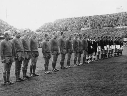 en lång rad med fotbollsspelare står på en fotbollsplan.