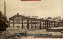 Exteriör, vy över stor verkstadsbyggnad, J & C G Bolinders Mekaniska Verkstads AB, från andra sidan Klara sjö. I förgrunden ångbåtsbrygga.