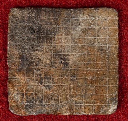 Medeltida spelbricka av bly med 12 x 12 rutor inristade. 
