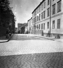 En kvinna med två barn passerar staketet vid Maria Folkskola. Timmermansgatan går norrut från Wollmar Yxkullsgatan