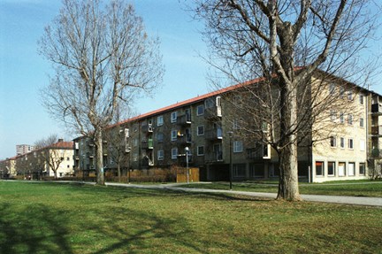 En öppen gräsbevuxen plats och bostadslängor.