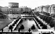 Stockholms stadsbibliotek med den stora dammen i förgrunden. Till höger i bild ligger Sveavägen.