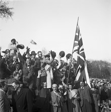Fredsdagen den 7:e maj 1945. 
Glada viftande människor firar freden.