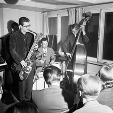 Rådmansgatan 24/Birger Jarlsgatan 64, Svenska Shell. Ett jazzband spelar under möte mellan Stockholms jazzklubbar. Saxofonister: Max Brühl och Lasse Gullin. Trummis: Birger Landström