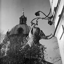 Östermalmskällarens skylt i hörnet av Jungfrugatan 1 med Hedvig Eleonora kyrkas torn i fonden