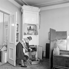 Blasieholmstorg 12. Annastina Alkmans hem. Hembiträdet häller kol i kaminen.