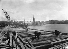 Timmermän i arbete med bjälklagen på södra längan. Utsikt över Riddarholmen och Södermalm.