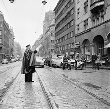 Vasagatan. En trafikpolis står mitt i gatan och dirigerar trafiken. Vy Vasagatan norr ut mot Norra Bantorget. (T. h. kvarteret Svanen och kvarteret Blåmannen, Centralposthuset).