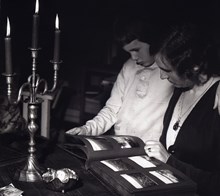 Reklambild (stämningsbild) med stearinljus och fotoalbum. Med kvinna och barn.