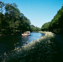 Vy från Djurgården (strax öster om Djurgårdsbrunnsbron) åt öster mot Djurgårdsbrunnskanalen. Rundtursbåt på väg mot Lilla Sjötullen