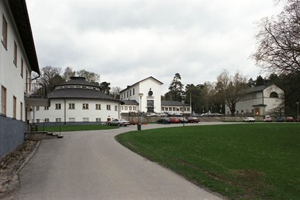 Vita stenbyggnader kring en gräsmatta.