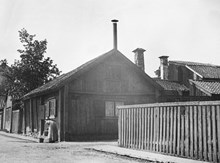 Västgötagatan 18 och 20  (nu Tjurbergsgatan 38) vid hörnet av Holländarevägen. En kvinna med ok fyller vatten i hinkar