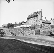 Hantverkargatan 26 (nu 54) västerut från hörnet av Polhemsgatan. Trapporna leder till Bergsgränd 3 (nu Polhemsgatan 21). En stor mängd tvätt hänger ute på tork.