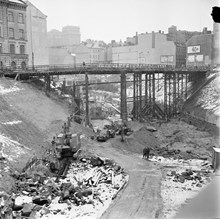 Vy norrut från Klarabergsgatan över rivningar och tunnelbanebygge kring platsen för blivande Sergels Torg. Mäster Samuelsgatan går via tillfällig bro.