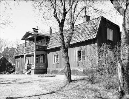 ett stort trähus på en höjd med en tvåvånings veranda.