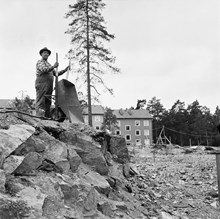 Blackeberg. En man med en skottkärra vid byggområde