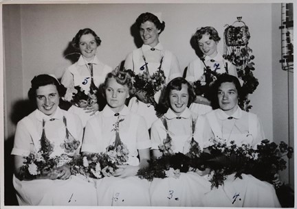 Svartvitt fotografi på flickor med blommor från Stockholms stads barnavårdsskola