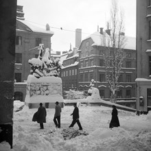 Några personer korsar Köpmantorget. Sankt Göran och draken är snötäckt