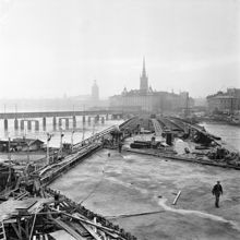 Byggnation av tunnelbanebron mellan Slussen och Gamla Stan. I förgrunden Sjöbergsplan och i fonden Riddarholmen och Riddarholmskyrkan.