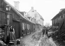 Stigbergsgatan österut. Hilma Borin hämtar vatten vid en vattenpost. Pojkarna ute i gatan är två av Hilmas fem barn, Helmer och John. T.h. Stigbergsgatan 36, platsen för blivande Navigationsskolan.
