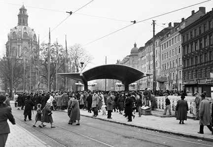Det välvda taket över tunnelbanenedgången syns över folksamlingen. Gustav Vasa kyrka i bakgrunden.