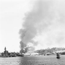 Galärvarvet, vy från Ladugårdslandsviken. Virkesförrådsbyggnaden i brand