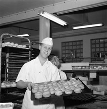 En bagargesäll visar upp en plåt med bullar