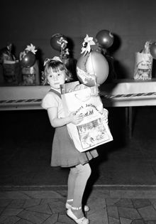 Hantverkargatan 1, Stadshuset. Sällskapet Jultomtarnas julfest. 5-åriga Maj Johansson med en påse presenter