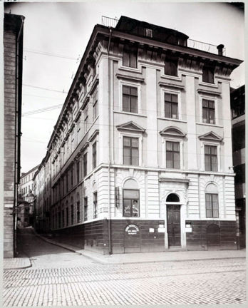 fastighet med fasad mot skeppsbron. gatan är stenbelagd.