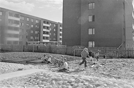 Lekande barn med två flerfamiljshus i bakgrunden.
