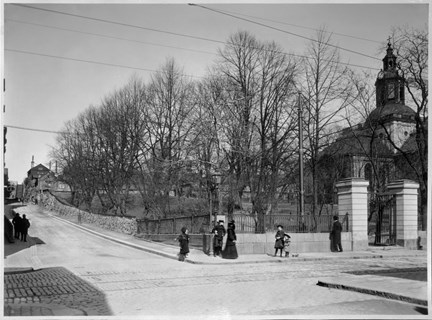 Människor passerar utanför kyrkans mur.