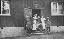 Nödbostäder i Stadshagen. Grupporträtt av barn och vuxna på trappan framför ytterdörr