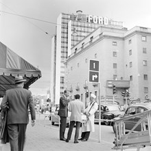 Sveavägen söderut vid Kungsgatan. T.h. Konserthuset. Korvgubbe med låda på magen samt kunder