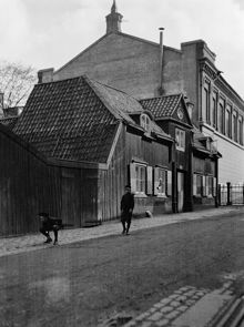 Ragvaldsgatan 21 söderut mot Södra Latins läroverk. Två pojkar leker vid porten till gården. Huset revs 1912. Södra Latin invigdes 1891 och är idag Södra Latins gymnasium