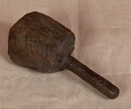 Medeltida murarklubba med fyrkantigt huvud. Fotograferad mot gråbrun bakgrund.